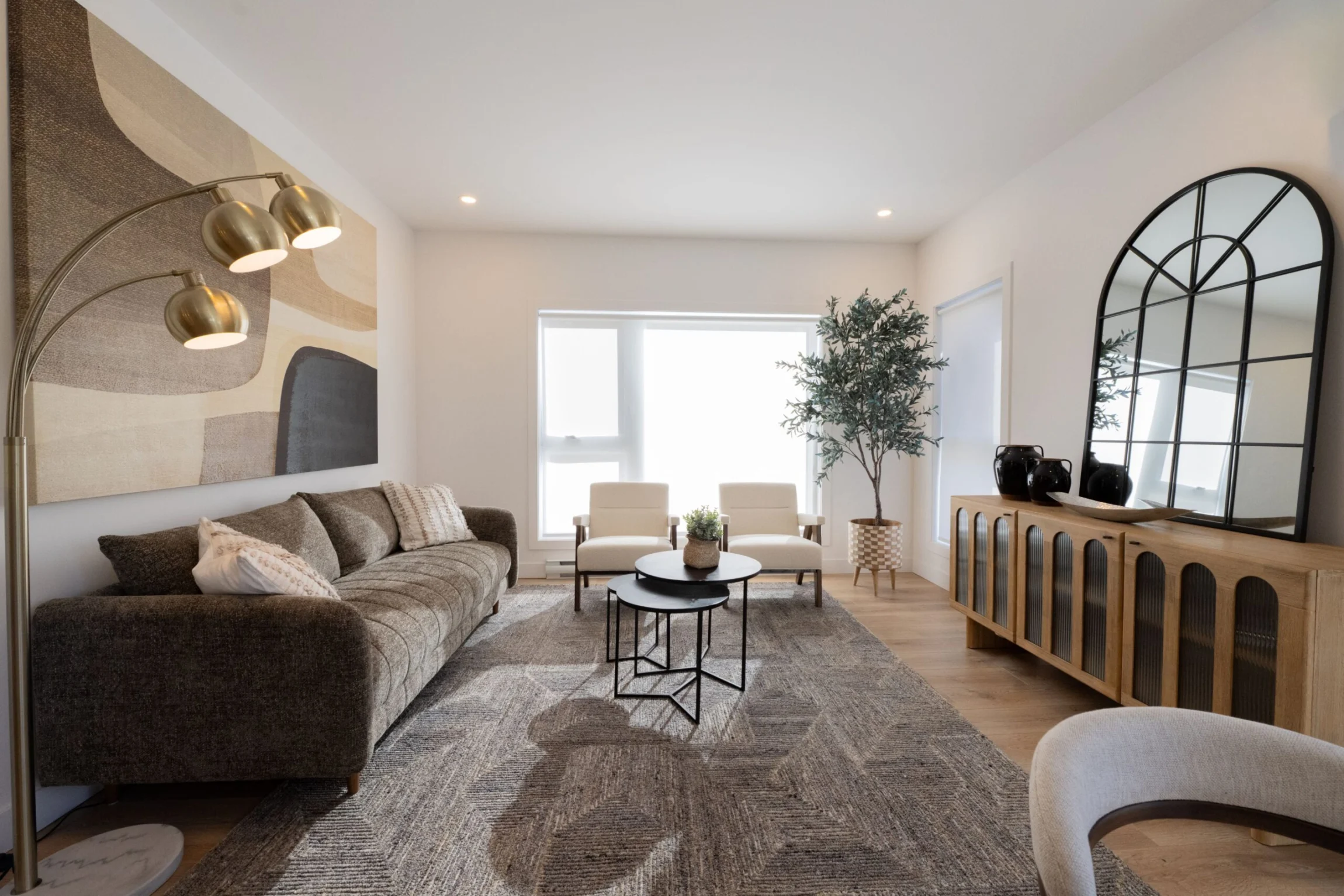 Salon raffiné avec miroir arqué, canapé neutre et lumière douce.