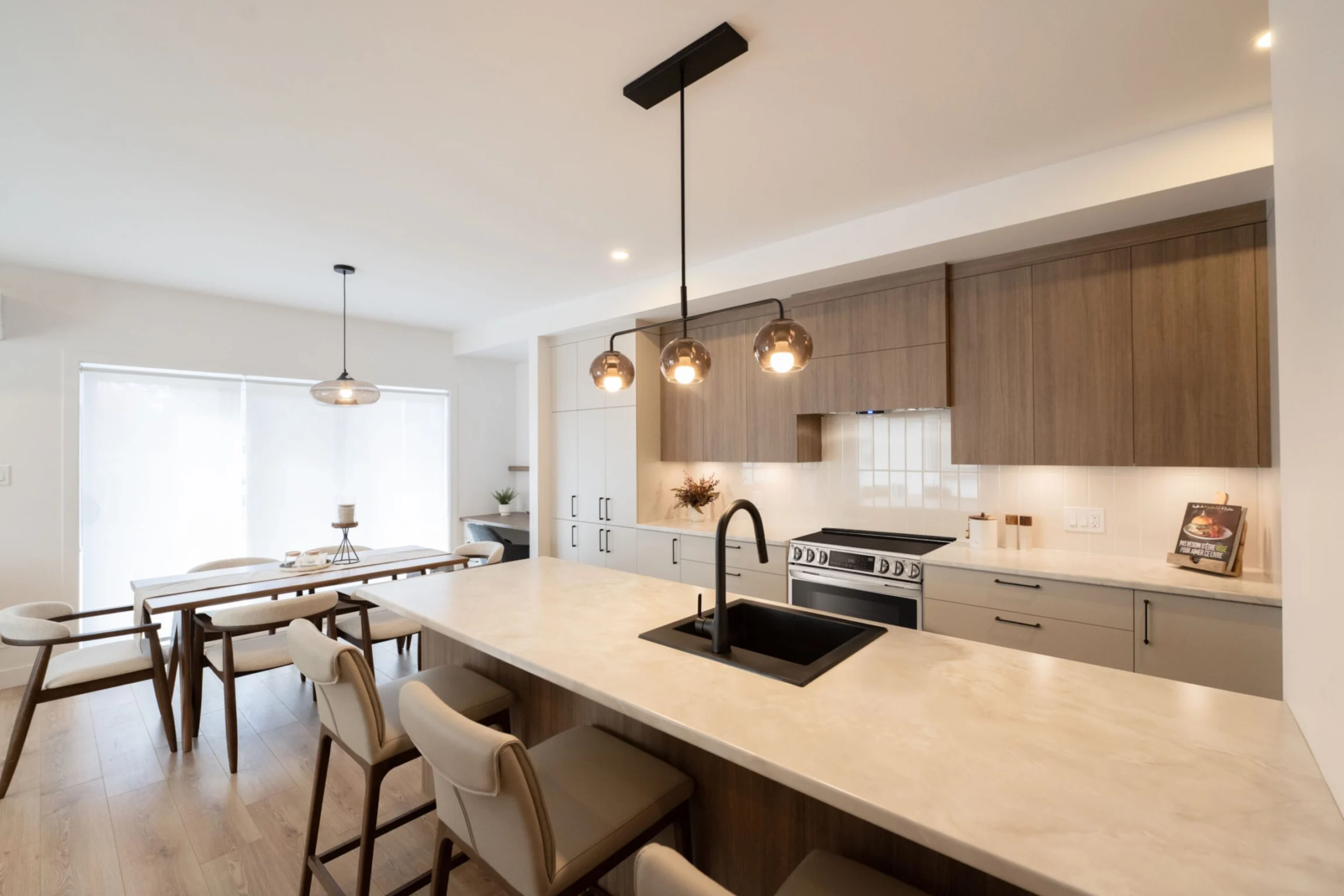 Cuisine contemporaine d'un condo du Quartier Horizon : îlot de quartz, cabinetterie de chêne, robinetterie noire mate.