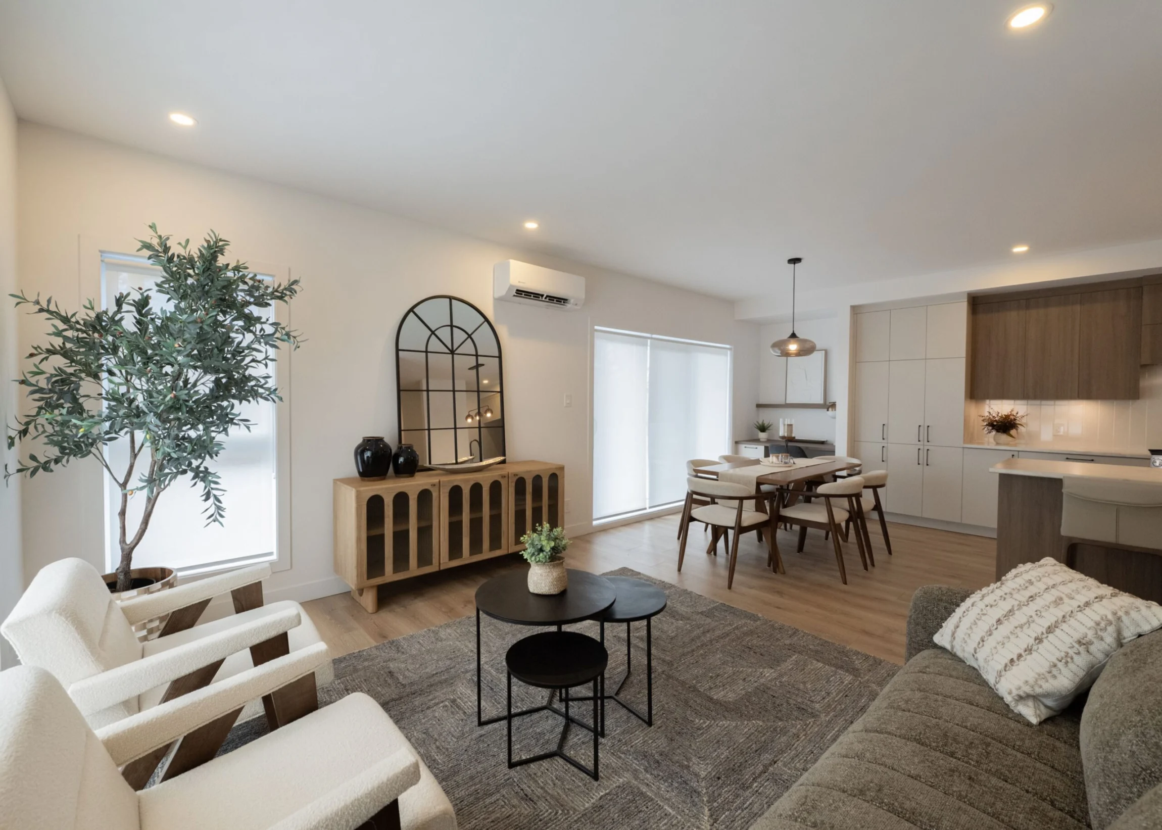 Salon lumineux avec grande plante verte, mobilier neutre et ambiance contemporaine.